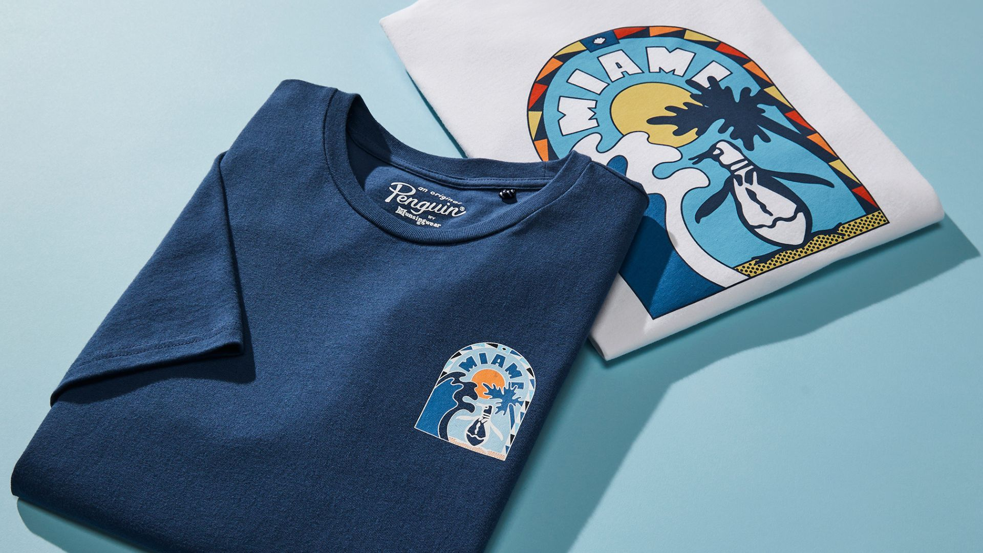 Varias camisetas de Original Penguin sobre un fondo azul